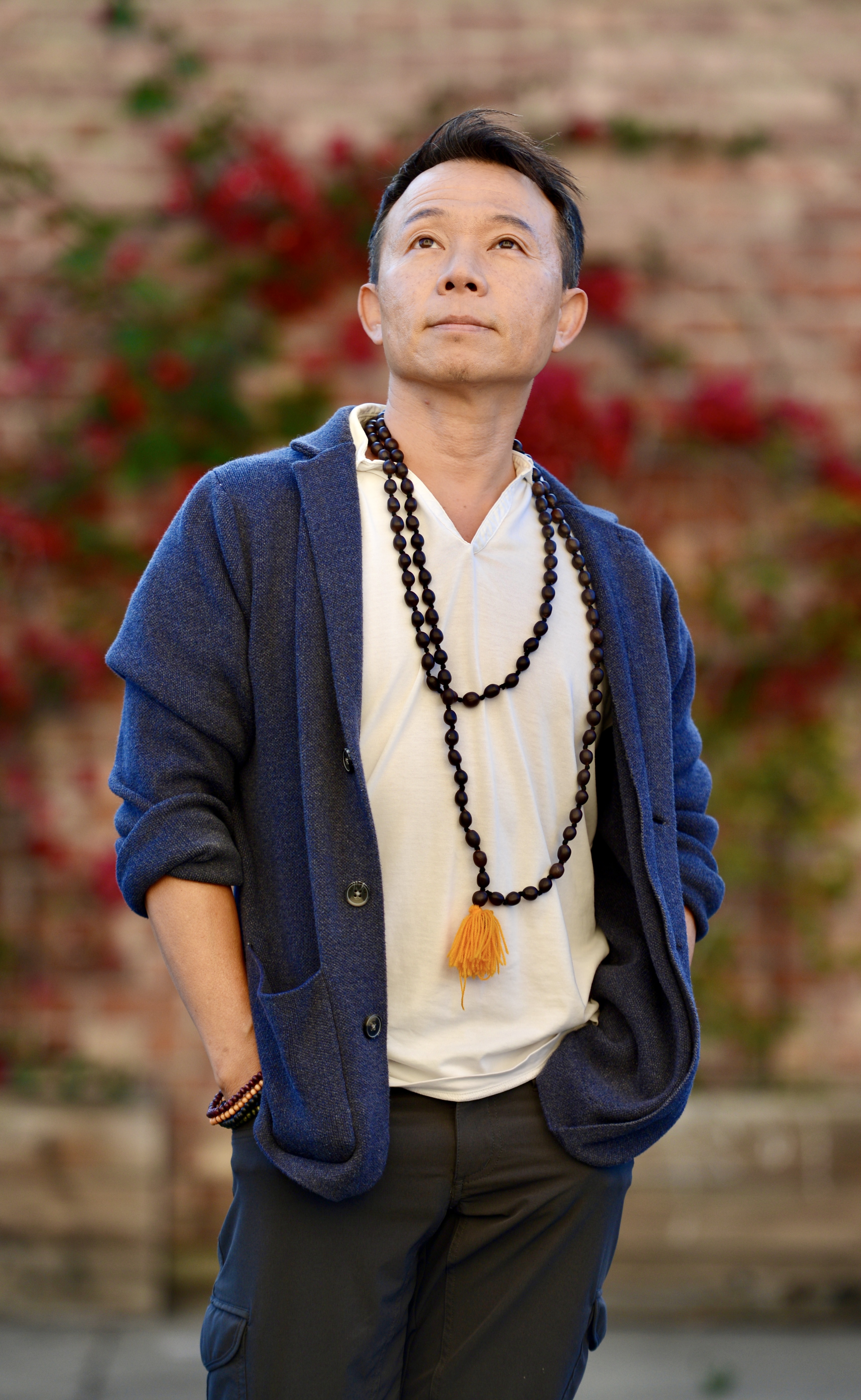 David Cho portrait, wearing mala beads and a blue jacket